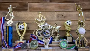 Collection de trophées et médailles sportives posés sur un fond en bois rustique.