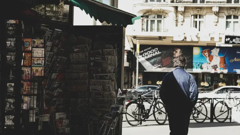 Un kiosque à journaux parisien typique avec des publications locales en plein air.