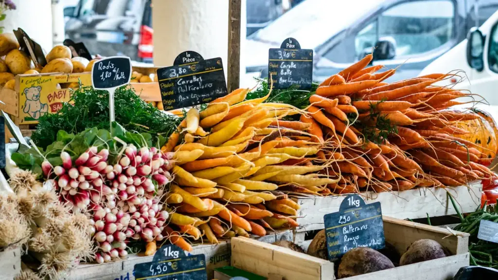 Étal de marché français avec des légumes frais, radis et carottes, prêts à cuisiner.