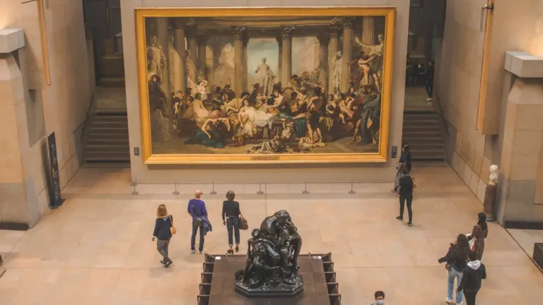 Visiteurs observant une grande peinture classique dans une salle de musée à Paris.