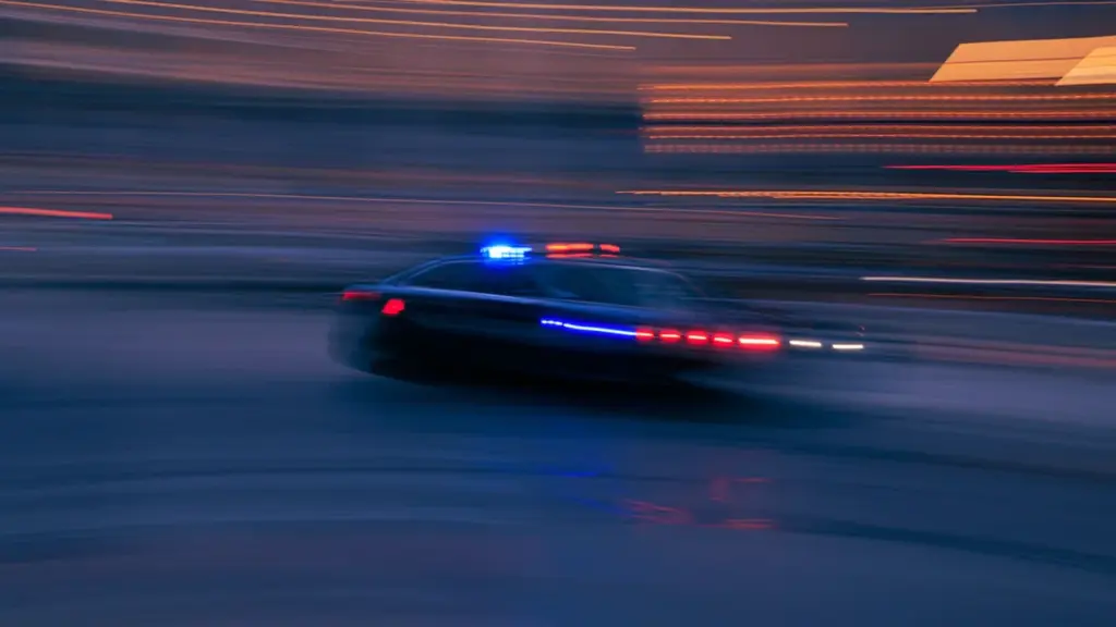 Voiture de patrouille circulant rapidement dans les rues de la ville la nuit.