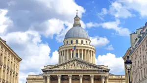 Vue majestueuse du Panthéon à Paris avec le drapeau français flottant sous un ciel bleu.