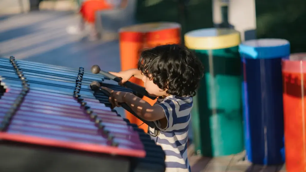 Un jeune garçon joue joyeusement du xylophone lors d'un atelier musical en extérieur.