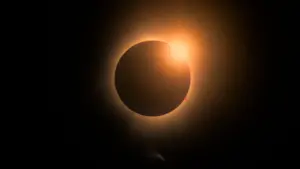 Une éclipse solaire totale avec un disque noir entouré d'une fine couronne lumineuse dorée.