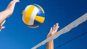 Deux joueurs de volley-ball s'apprêtent à frapper un ballon coloré au-dessus du filet.