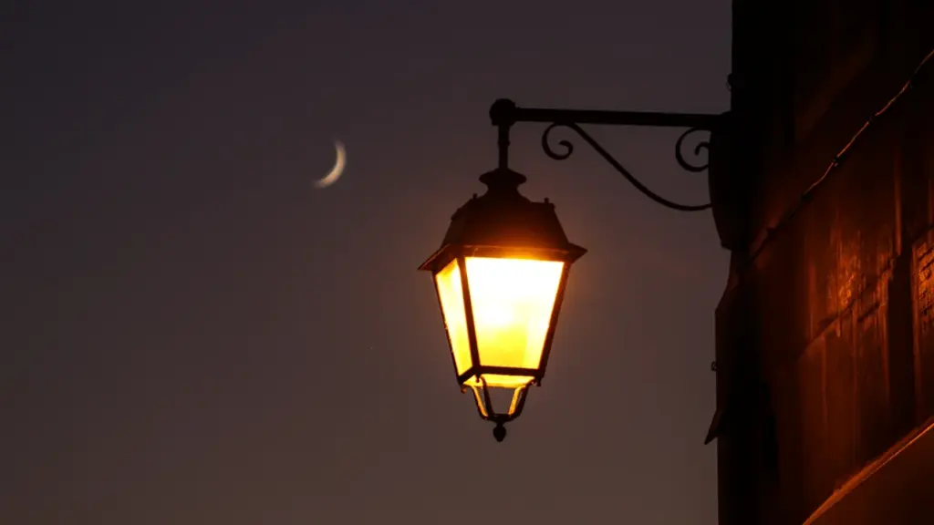 Lanterne ancienne éclairée la nuit avec un croissant de lune dans le ciel.