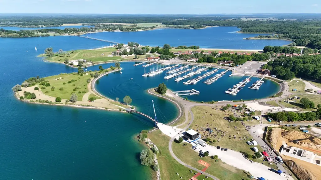 Vue aérienne d'une marina avec de nombreux bateaux amarrés dans un lac entouré de verdure.