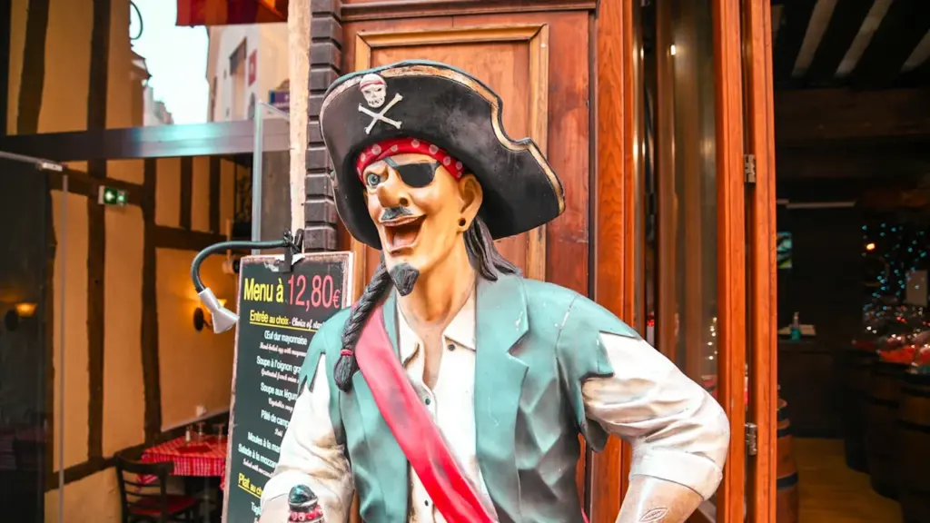 Une statue de pirate accueillante devant un restaurant traditionnel à l'architecture normande française.