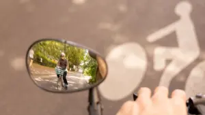 Un cycliste portant un casque est visible dans le rétroviseur d'un vélo sur la route.