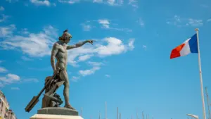 Statue de marin devant le drapeau français dans le port de Toulon.