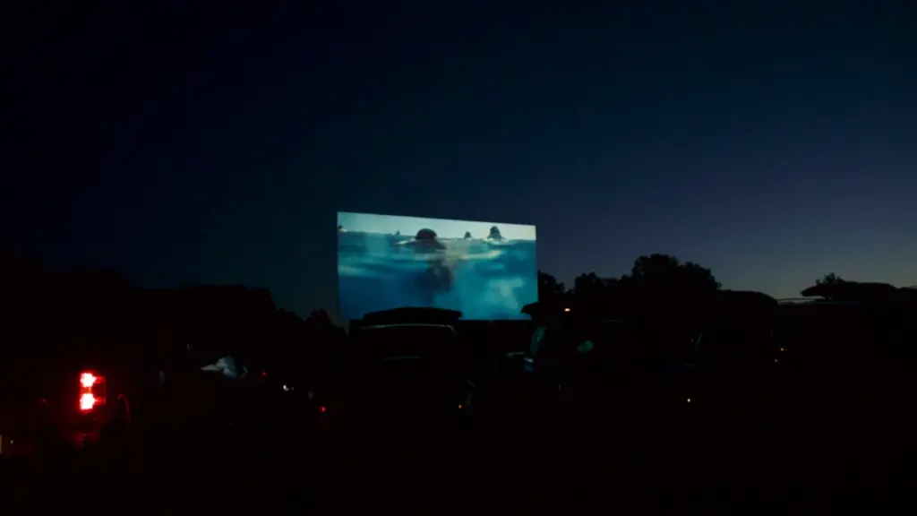 Un écran de cinéma en plein air projetant un film sous un ciel nocturne.