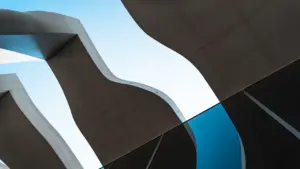 Vue architecturale en contre-plongée montrant des lignes courbes modernes et un ciel bleu.