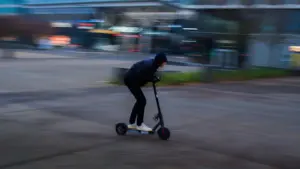 Un utilisateur circulant en trottinette électrique dans une rue française en journée.