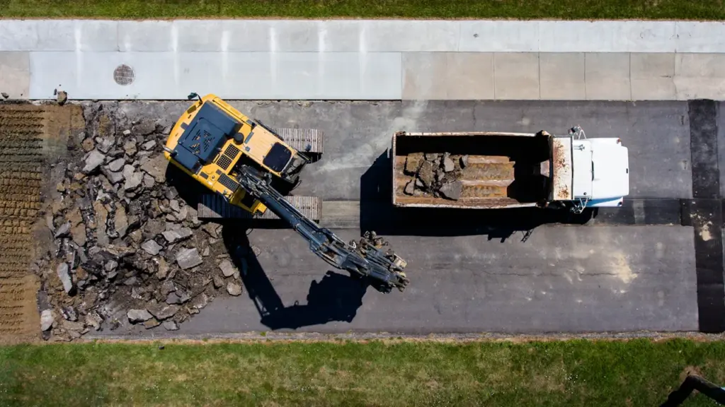 Vue aérienne d'une pelleteuse jaune retirant l'asphalte d'une rue en travaux à Metz.