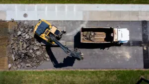 Vue aérienne d'une pelleteuse jaune retirant l'asphalte d'une rue en travaux à Metz.