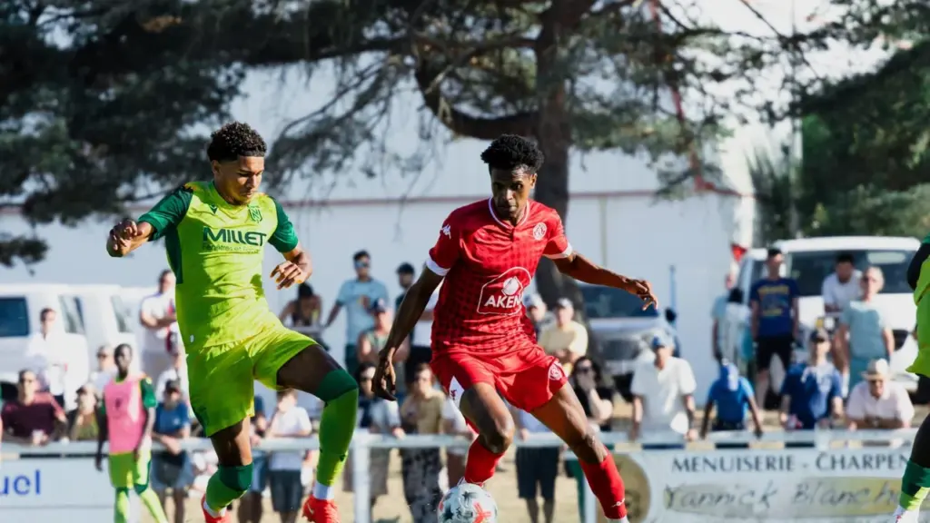 Deux joueurs de football en duel sur un terrain lors d'un match en plein air.