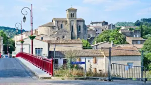 Un pont en pierre traversant une rivière près d'un village historique en France.
