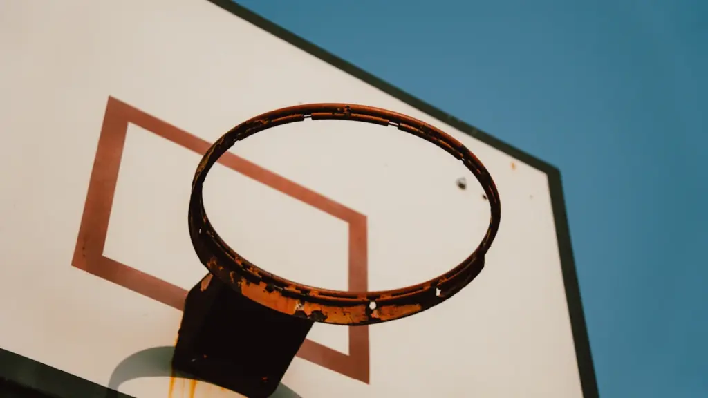 Panneau de basket extérieur avec filet sous un ciel bleu clair.