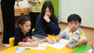 Un animateur accompagne des enfants lors d'une activité créative et pédagogique en atelier.