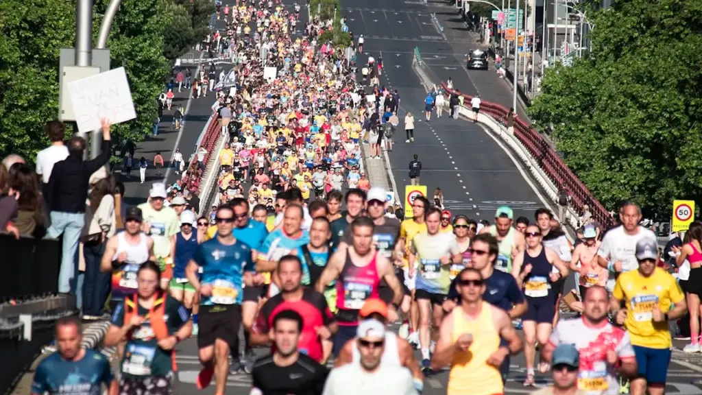 Une foule importante de coureurs participant à un marathon sur une route urbaine.