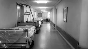Couloir d'hôpital avec des lits médicaux alignés dans une ambiance sobre et nostalgique.